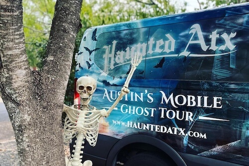 All the tour guides dressed up in spooky attire in front of the public van